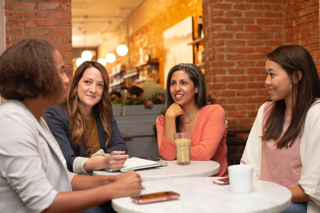 Zu sehen sind Frauen an einem Tisch sitzend, die wegen Businesscoaching für Frauen zusammensitzen.